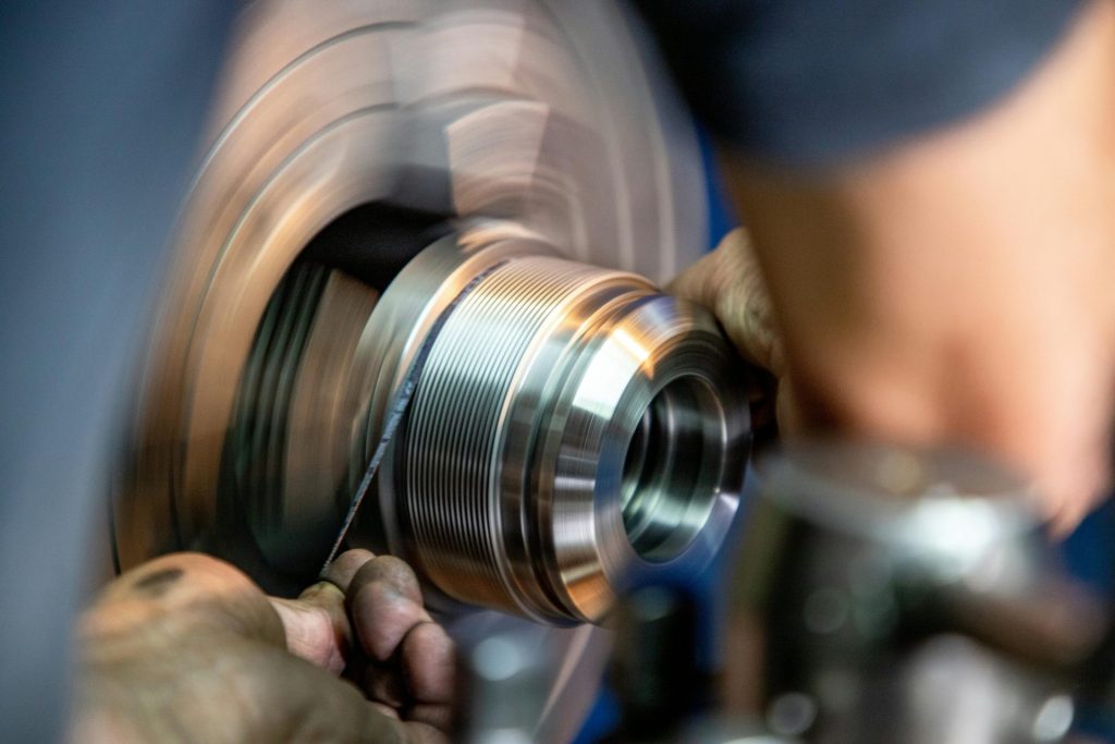 Nahaufnahme eines Arbeiters beim Metallschleifen, die Präzision und handwerkliches Können im industriellen Umfeld demonstriert.