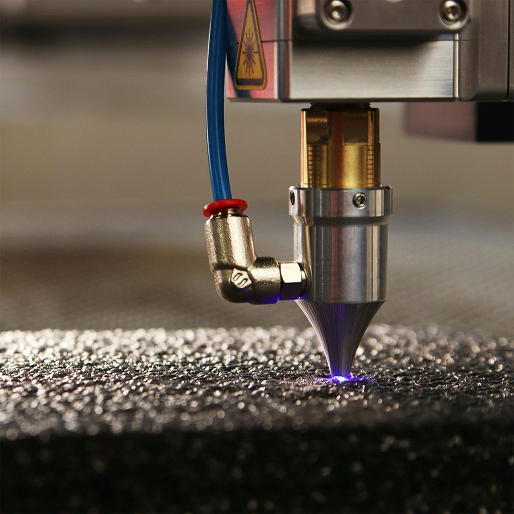 Nahaufnahme eines hochpräzisen Lasergravierers beim Bearbeiten einer strukturierten Oberfläche.